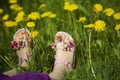 Young girl lying on grass in the middle of dandelions in sunlight with painted toe nails