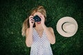 Young girl lying on the grass taking a picture of the sky with her camera, next to her is a hat Royalty Free Stock Photo