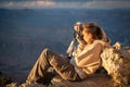 young girl lying on the ground of the precipice of the grand canyon taking photos at the golden hour