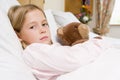 Young Girl Lying In Hospital Bed With Teddy Bear