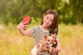 A young girl makes a selfie on a smartphone with dogs in nature