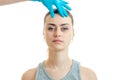 Young girl without makeup stands up straight and the doctor in a blue glove touches her face close-up Royalty Free Stock Photo