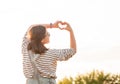 Pretty girl making hands in heart shape in sunset