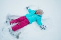 A young girl making snow angels