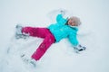 A young girl making snow angels