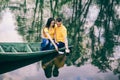 Young girl and man sitting together in old wooden boat on river. Royalty Free Stock Photo