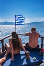 Young girl and man sun bathing in front of Greek flag on boat de Royalty Free Stock Photo