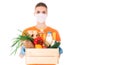 Young girl in a mask and an orange t-shirt holds a wooden box with groceries for delivery isolated on white background Royalty Free Stock Photo