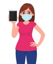 Young girl in medical face mask showing tablet computer. Woman holding digital gadget or pad. Female character. Corona virus