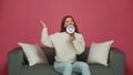 Young girl with megaphone proclaim news, announce advertisement, using loudspeaker, sitting on sofa