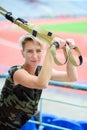 Young girl doing exercises outdoors using slings, TRX loop