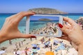 Young girl with mobile phone photographs Cala Conta beach in Ibiza Island