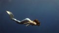 Young girl model underwater mermaid costume on blue background poses in Red Sea.