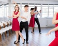 Young girl with multinational group of active people dancing couple enjoying active swing during dance party in ballroom Royalty Free Stock Photo