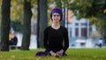 Young girl muslim woman in hijab sits on green grass in park takes leg by foot bends turns to side stretching doing