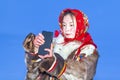 A young girl, in the national winter clothes of the northern inhabitants of the tundra, takes a selfie on a smartphone Royalty Free Stock Photo