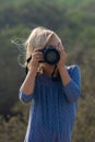 Young girl in nature taking pictures with a large dslr and a zoon lens Royalty Free Stock Photo