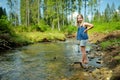 Young girl near cold shallow stream winding through majestic pine trees of Tatra mountain range near Zakopane, Poland Royalty Free Stock Photo