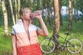 Young girl next to her bike drinking water with bottle in park Royalty Free Stock Photo