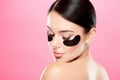 Young girl with nude make up and naked shoulders at studio background,black eye patches on face, beauty photo concept