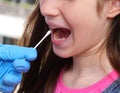 Young girl with open mouth during diagnosis for coronavirus research with an oropharyngeal swab Royalty Free Stock Photo