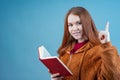 a young girl with an open red book in her hands smiles at the camera Royalty Free Stock Photo