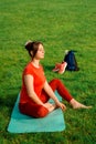 A young girl in orange sportswear for yoga or stretching sitting on a yoga mat in a resting relaxing position with closed eyes. Royalty Free Stock Photo