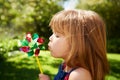 Young girl, outdoor and blowing pinwheel, garden and enjoying freedom of outside and happy. Pretty little child Royalty Free Stock Photo