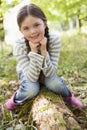 Young girl outdoors in woods sitting on log Royalty Free Stock Photo