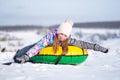 Little girl enjoying snow tubing at sunny weather