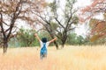 Girl With Overalls and Black Hat Standing in Field With Arms Raised Royalty Free Stock Photo