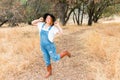 Girl With Overalls and Black Hat Standing in Field With Arms Raised Royalty Free Stock Photo