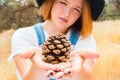 Young Girl in Overalls Holding up a Pinecone