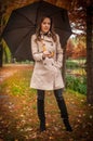 young girl in overcoat in forest. Fashion woman in coat in park. Slim young fashion model wearing white coat outdoor.