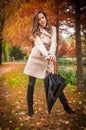 young girl in overcoat in forest. Fashion woman in coat in park. Slim young fashion model wearing white coat outdoor.