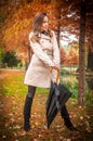 young girl in overcoat in forest. Fashion woman in coat in park. Slim young fashion model wearing white coat outdoor.