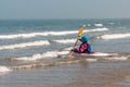 Young girl paddling kayak through surf out towards the sea on a sunny day Royalty Free Stock Photo