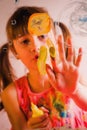 Young girl painting image on the glass with finger. Happiness, childhood, art, painting lessons concept. Vertical portrait Royalty Free Stock Photo