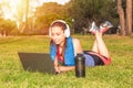 A young girl in a park on the grass After fitness training with laptop and headphones Royalty Free Stock Photo