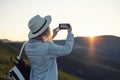 Young girl with a phone camera in the mountains during sunset. Girl and phone. Photographing landscapes by phone. Royalty Free Stock Photo