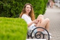 A young girl with phone in her hands, sits on a bench in the park and looked at the frame Royalty Free Stock Photo