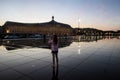 young girl photographing the Place de la Bourse and its reflection in a water mirror in Bordeaux in France Royalty Free Stock Photo