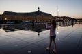 young girl photographing the Place de la Bourse and its reflection in a water mirror in Bordeaux in France Royalty Free Stock Photo