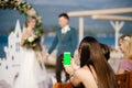 Young girl photographs the bride and groom on a smartphone. Blank screen