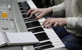 A young girl pianist plays the electronic piano with her favorite music. Female graceful hands touch the keys of the synthesizer c Royalty Free Stock Photo