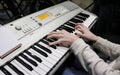 A young girl pianist plays the electronic piano with her favorite music. Female graceful hands touch the keys of the synthesizer c Royalty Free Stock Photo