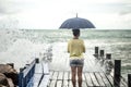 A young girl on a pier with an umbrella