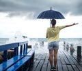 A young girl on a pier with an umbrella