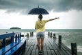 A young girl on a pier with an umbrella