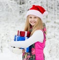 Young girl with pile gift boxes in winter forest